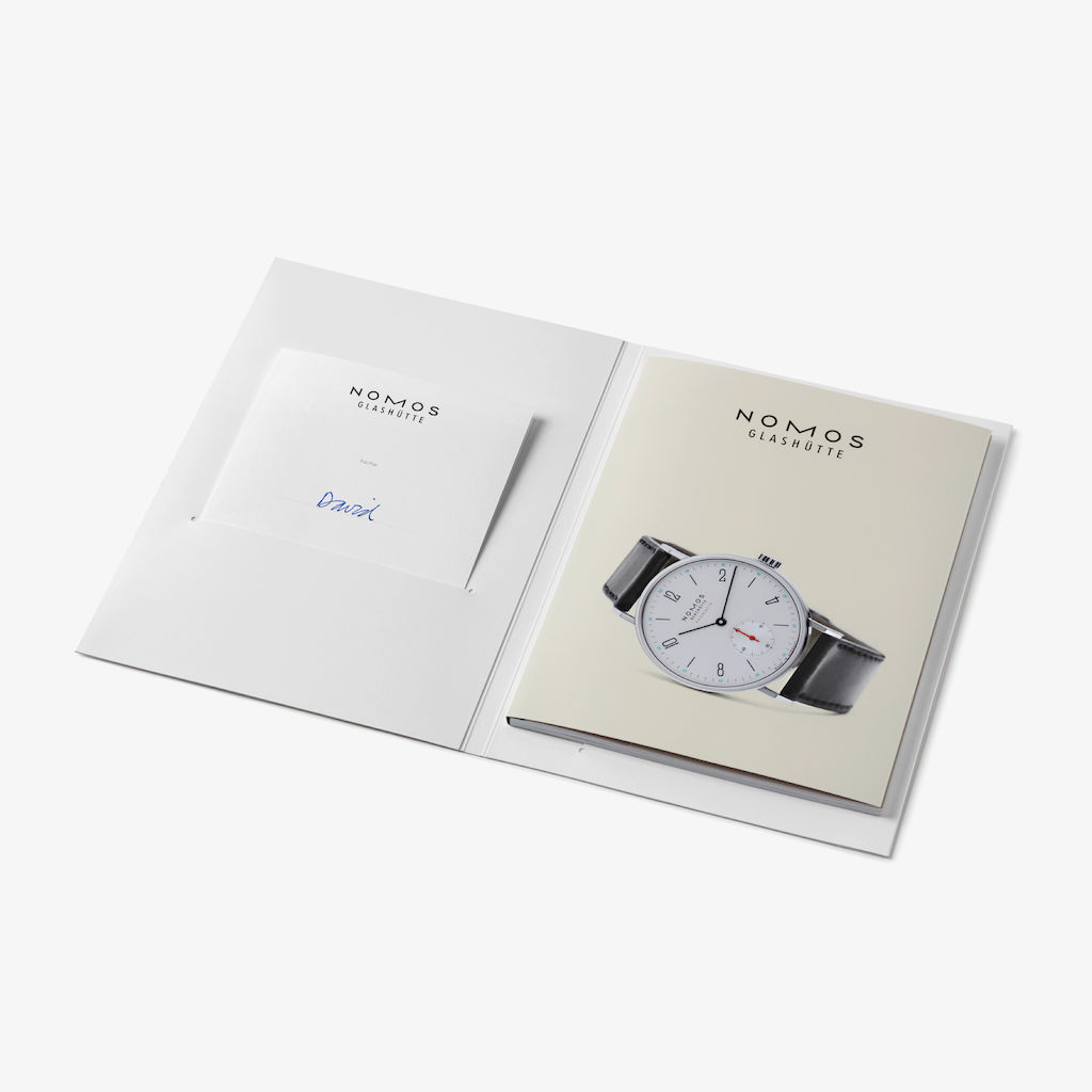 La tarjeta regalo de NOMOS puede canjearse en línea (en nomos-glashuette.com) o en la tienda principal de NOMOS, NOMOS Kaufhaus, en Glashütte (Alemania). Las tarjetas regalo tienen una validez de tres años, a contar desde el final del año en que se adquirieron. Dicho periodo de validez viene fijado por la legislación alemana. No obstante, si una tarjeta regalo no se canjea en dicho periodo, estaremos igualmente encantados de ayudarle.
Guarde bien esta tarjeta regalo y su código exclusivo, y evite que caiga en manos de personas no autorizadas. Lamentablemente, no podemos ofrecer sustituciones en caso de pérdida o robo de una tarjeta regalo. Para canjear esta tarjeta regalo, use el código que contiene durante el proceso de pedido en línea o bien en persona en la tienda principal de NOMOS. Una vez utilizado, el código dejará de ser válido. Esta tarjeta regalo puede transferirse a terceros.