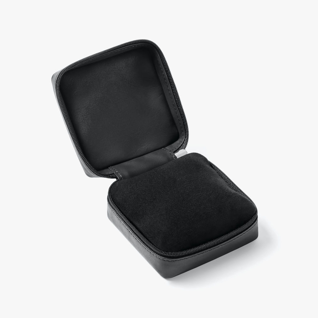 El logotipo de NOMOS en letras plateadas adorna la tapa de la caja del reloj. Por dentro está bien acolchado. También se incluye un paño de limpieza para eliminar las manchas de huellas dactilares del hermoso cristal de zafiro. Tamaño: 9 x 9 x 4,5 cm